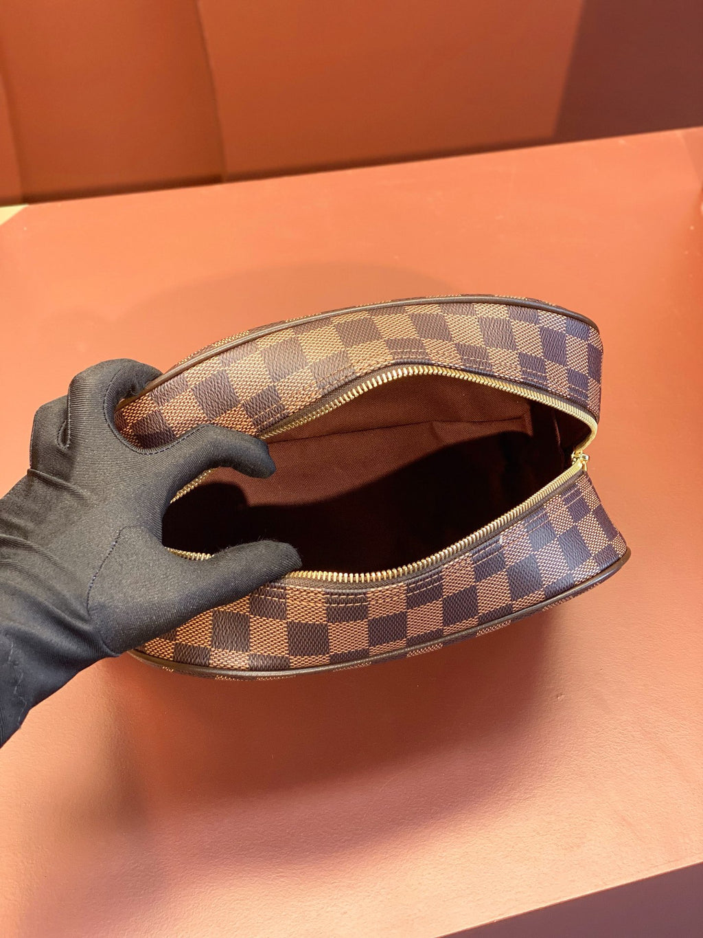 Louis Vuitton toiletry bag open at top, showing brown fabric interior lining.