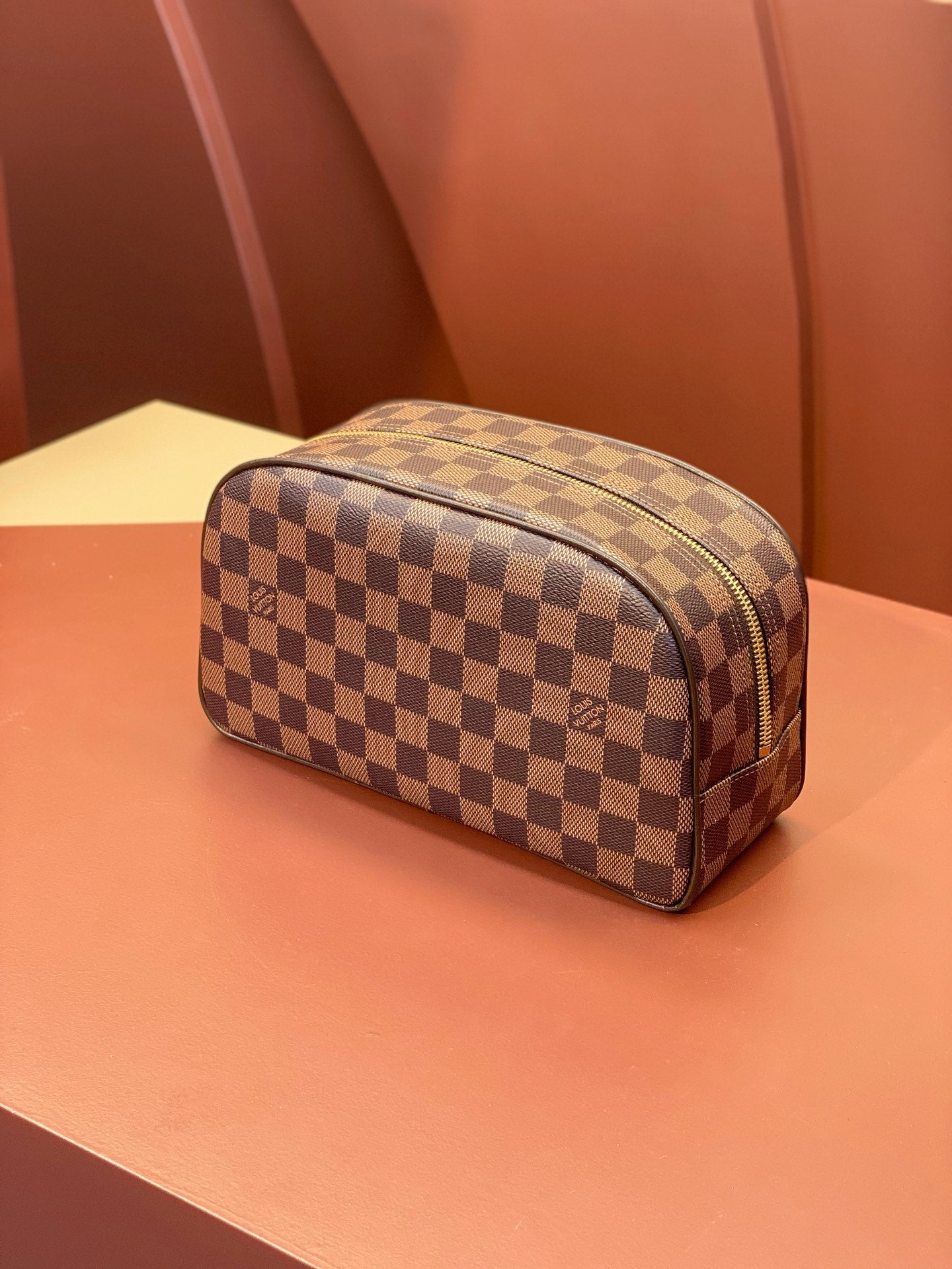 Louis Vuitton Damier checkered toiletry bag with top zip and rounded silhouette.