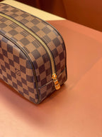 Louis Vuitton Damier checkered toiletry bag corner view with gold zipper pull.