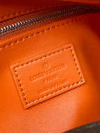 Louis Vuitton logo leather label on orange-trim bag, gold-tone text
