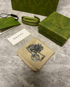 Silver-toned chain necklace with GG heart pendant on beige pouch