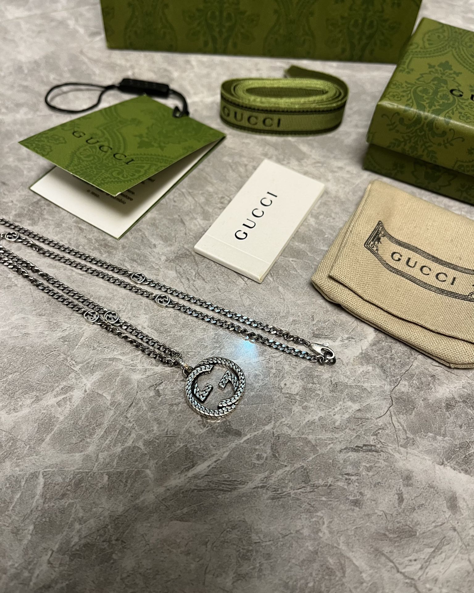Silver-toned chain necklace with GG heart pendant, flat lay