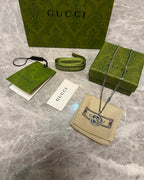 Silver-toned chain necklace with GG heart pendant on beige Gucci pouch