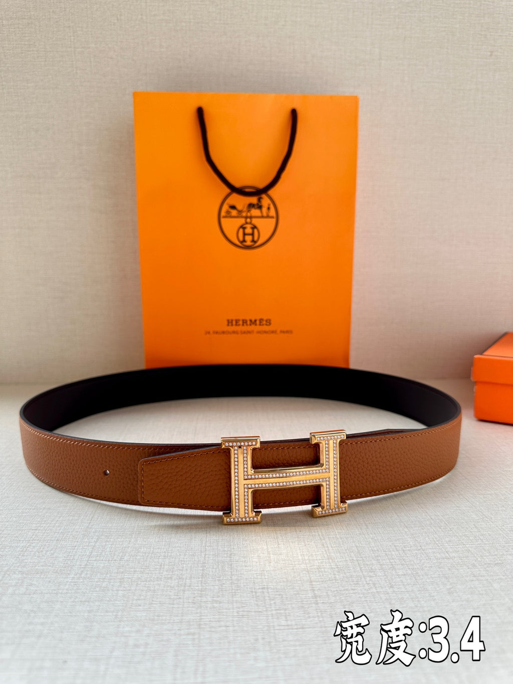 Brown leather belt with silver-toned H buckle featuring rhinestone border