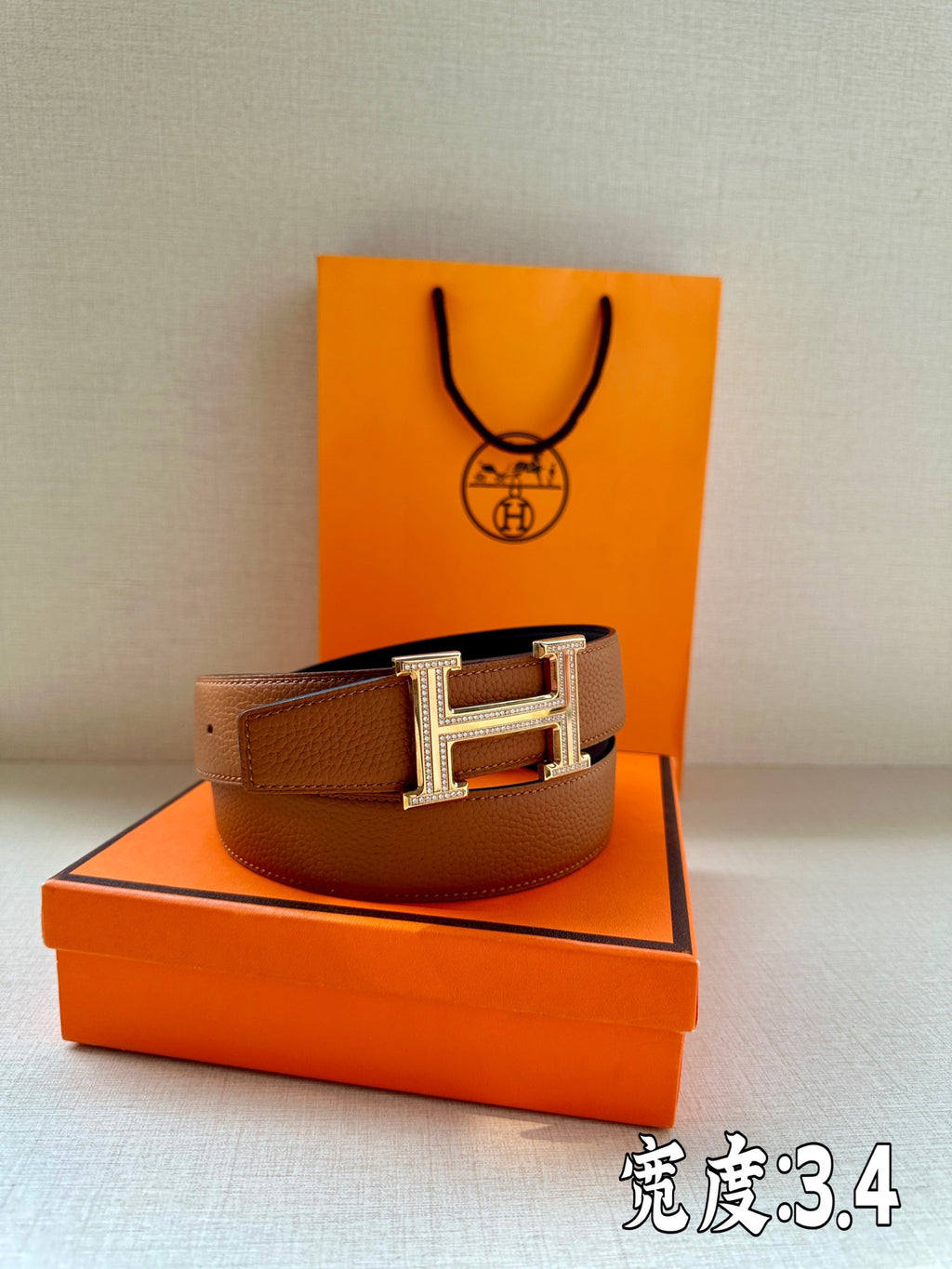 Brown leather belt with silver-toned H buckle, shown in a curved layout