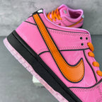 Pink low-top sneaker side view with orange strap detail, orange swoosh, and black sole
