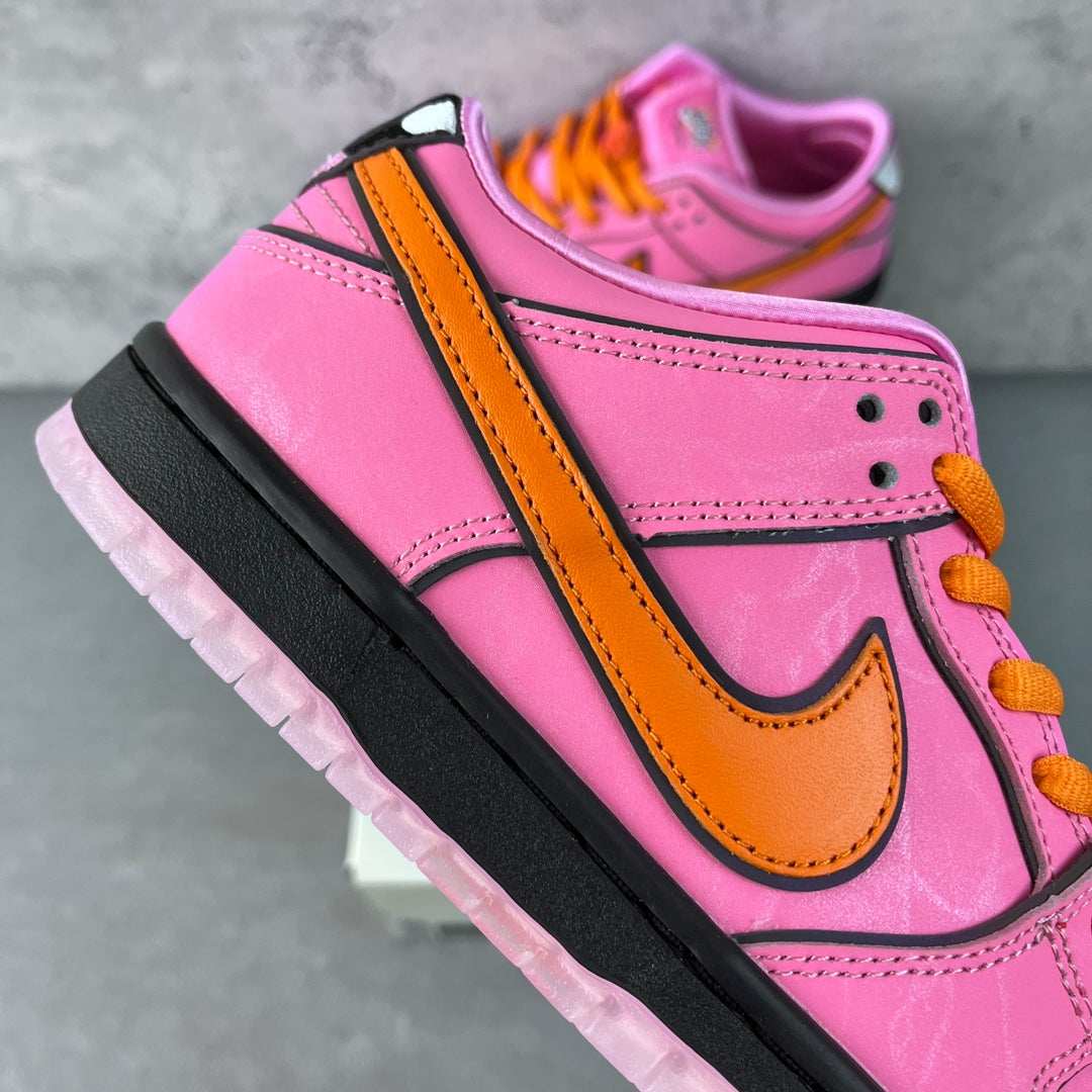 Pink low-top sneaker side view with orange strap detail, orange swoosh, and black sole