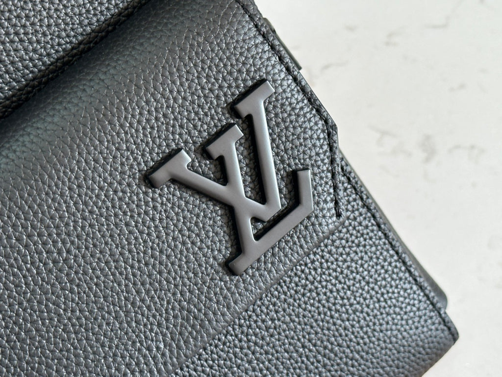Louis Vuitton leather bag flap with embossed LV logo on textured dark gray leather