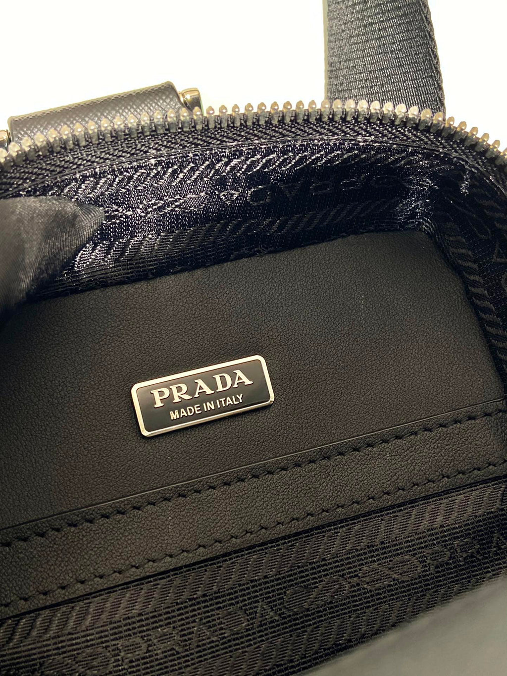 Prada black bag close-up of PRADA Made in Italy logo plaque and stitching