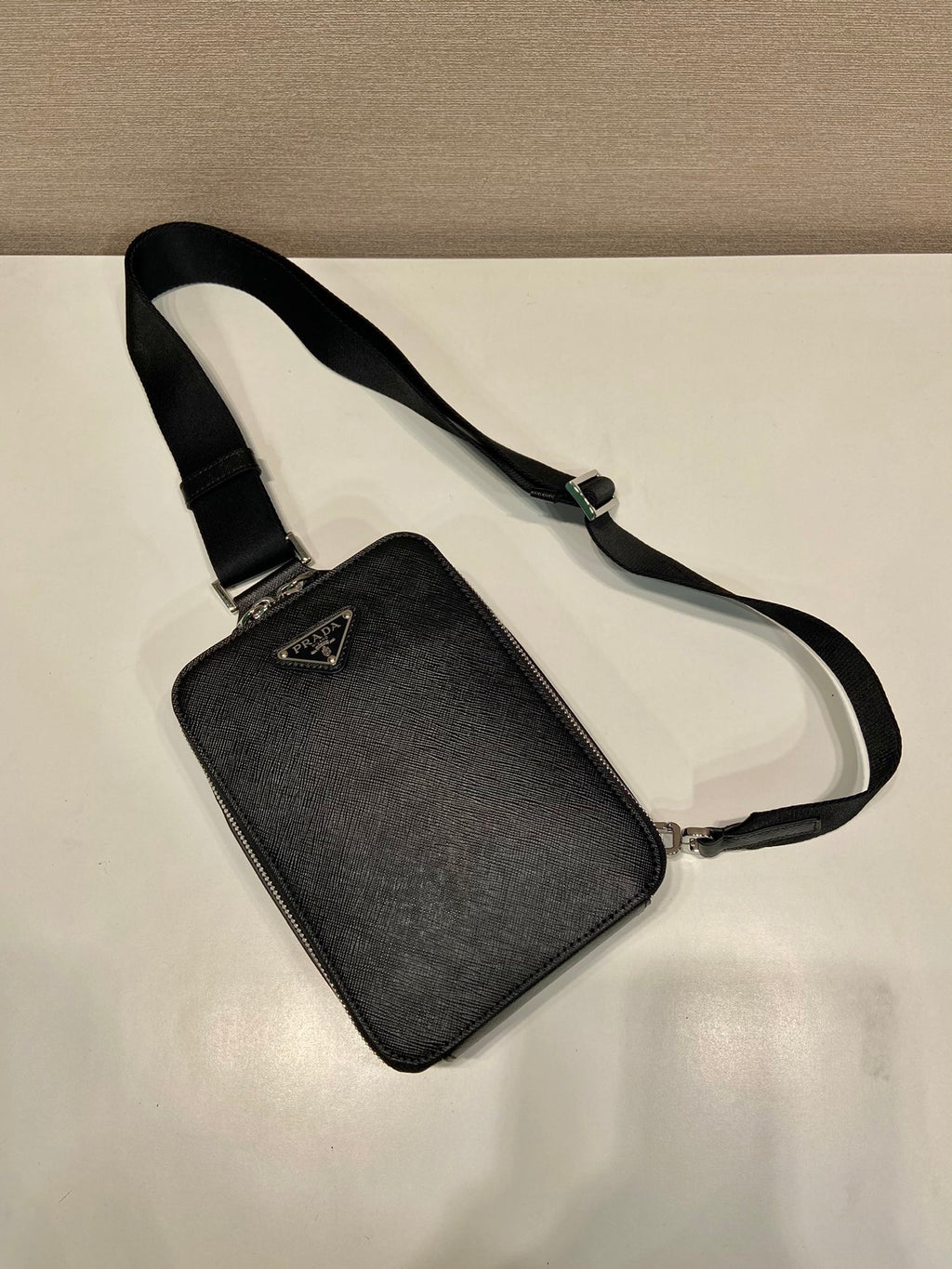 Prada black mini crossbody bag with adjustable strap and triangular logo plaque
