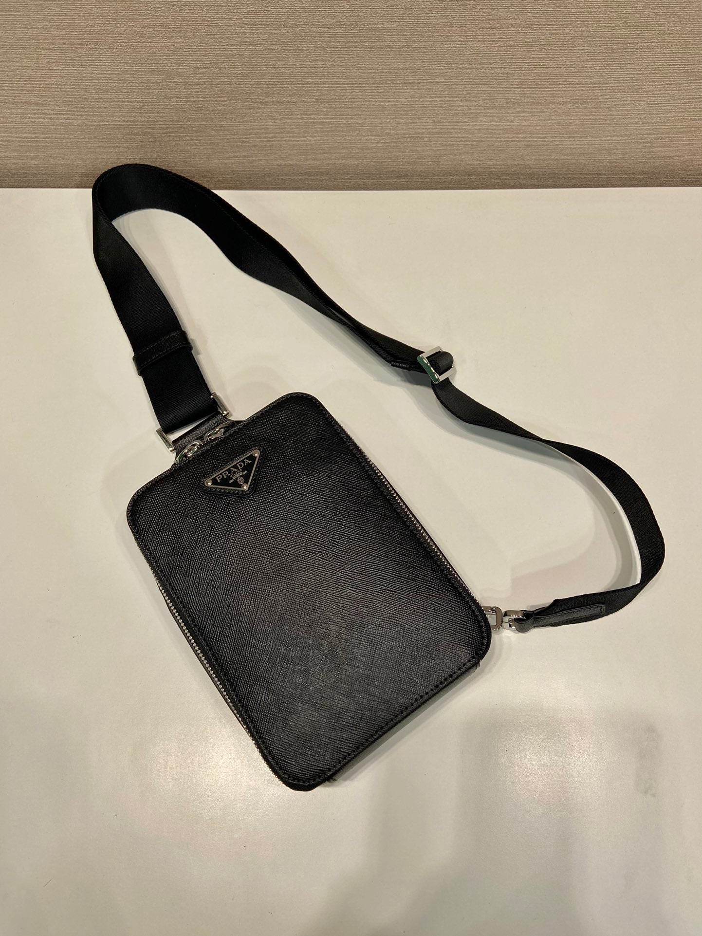 Prada black mini crossbody bag with adjustable strap and triangular logo plaque