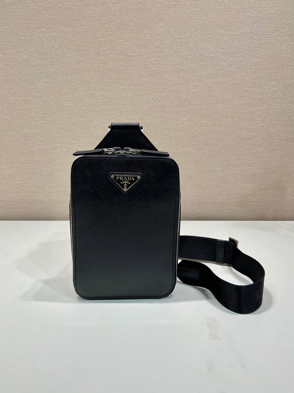 Prada black mini bag with flap front and adjustable shoulder strap, side view