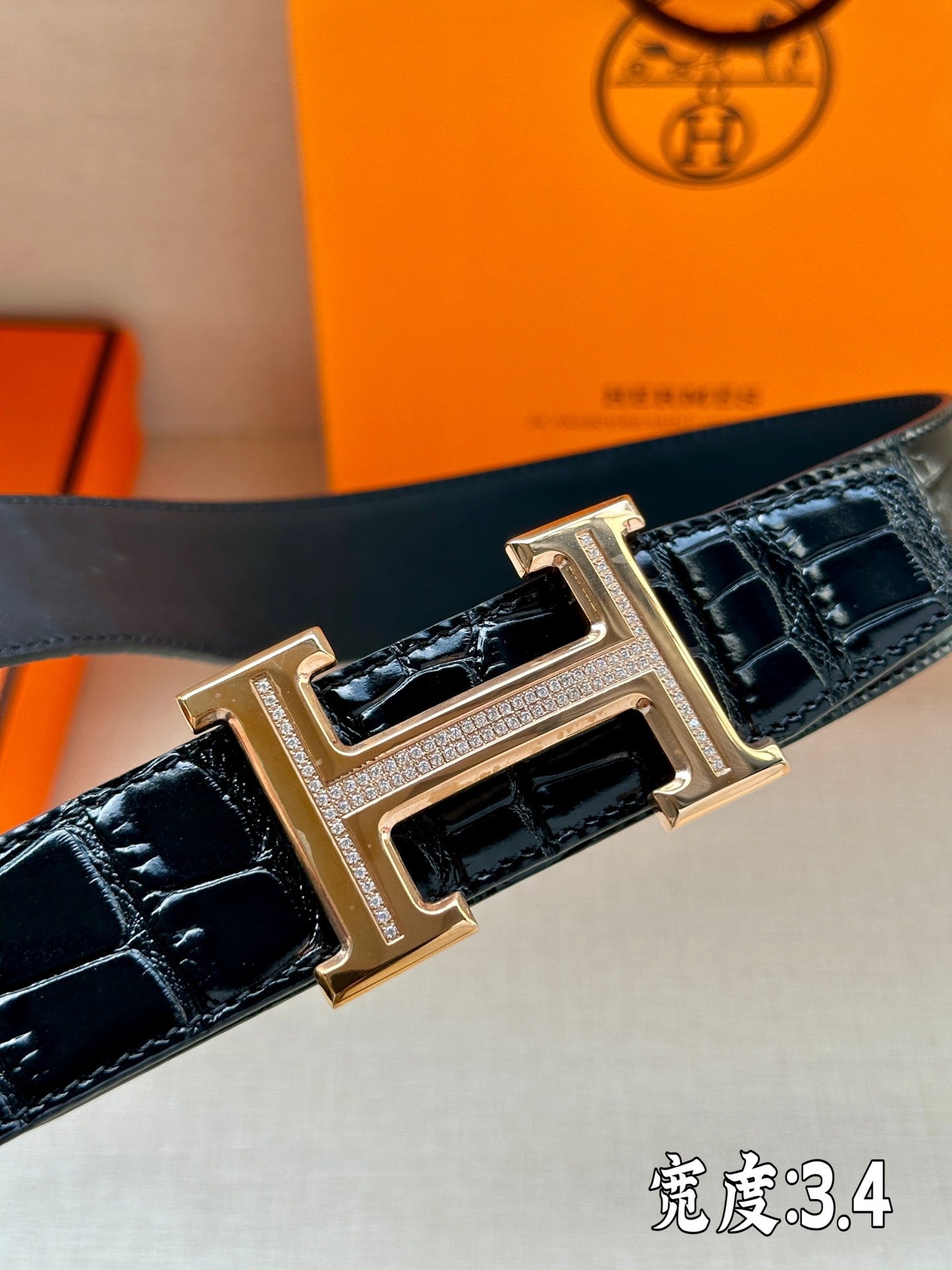 Hermes belt buckle with gold-tone H detail on embossed dark leather strap