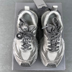 Pair of light gray Balenciaga sneakers in a box, lace-up front view