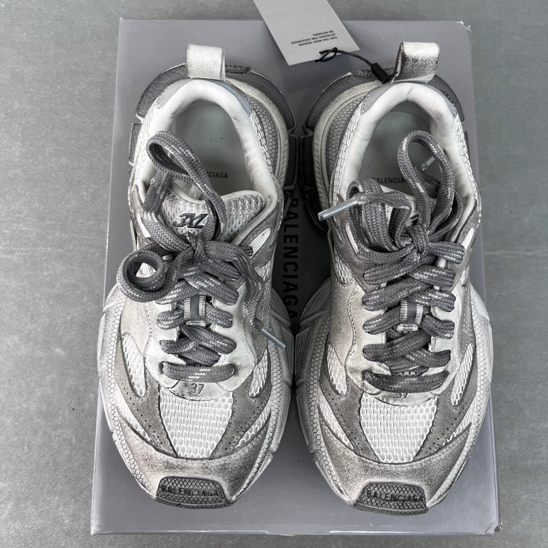 Pair of light gray Balenciaga sneakers in a box, lace-up front view