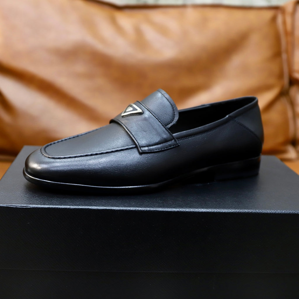 Black leather loafer with Prada triangle emblem, side profile on box