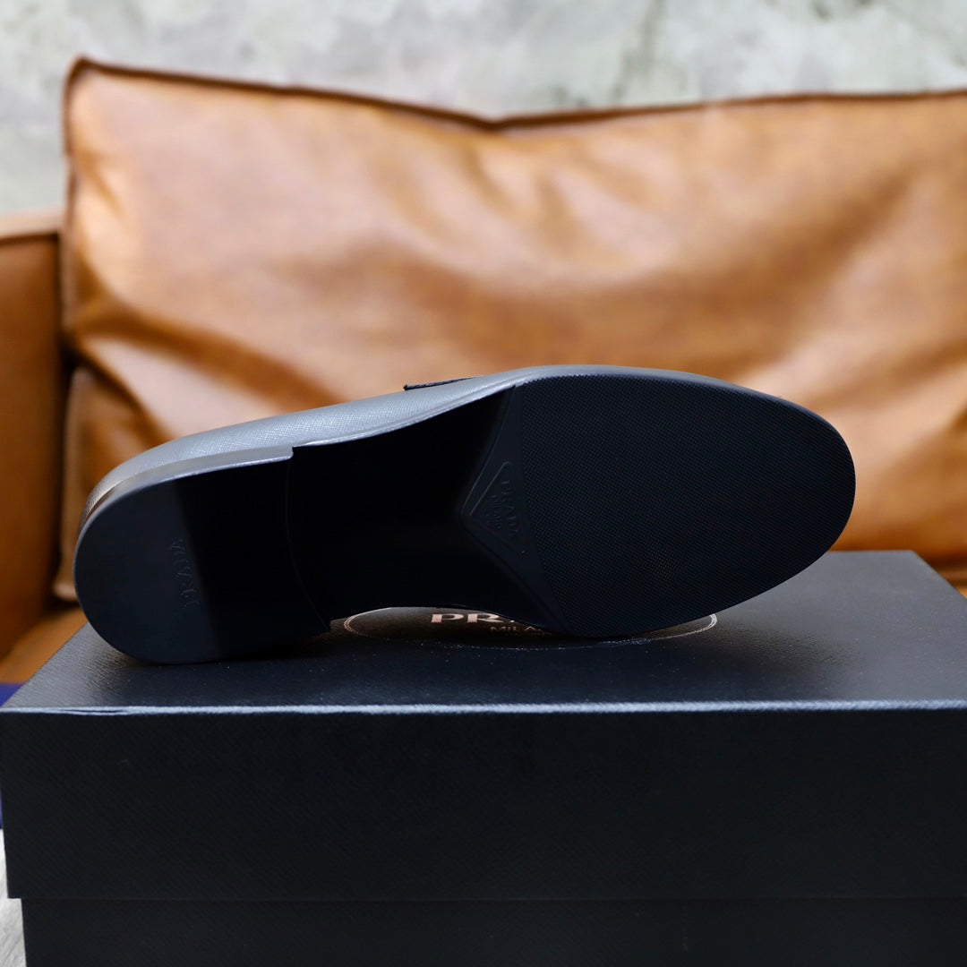 Unisex black leather loafers outsole view on a black shoe box
