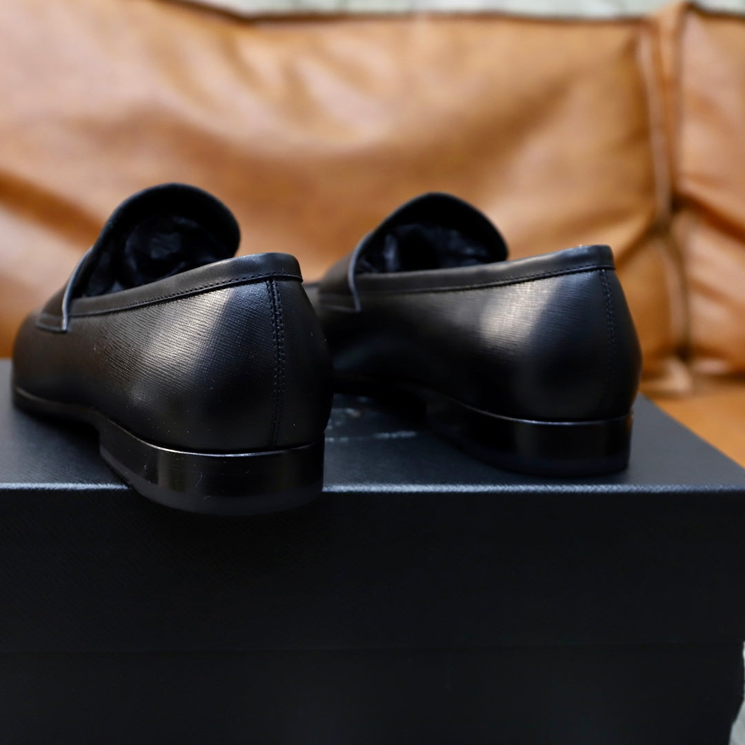 Unisex black leather loafers, heel and back view on a black display box