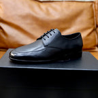 Prada black leather lace-up shoes on dark shoebox, side view