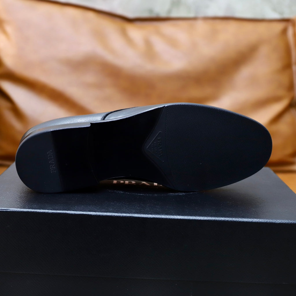 Prada black leather shoes, outsole view on dark shoebox