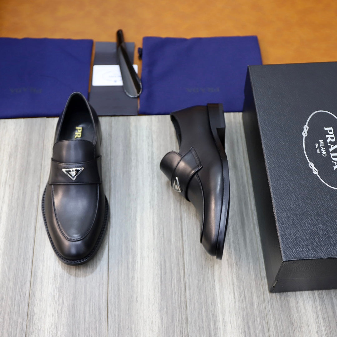 Prada unisex black leather loafers, angled view with logo strap and stitched sole