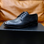 Black leather lace-up oxford shoe on black box, front view