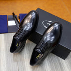 Prada unisex lace-up oxfords in dark shiny leather, close angle over black box.