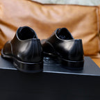Prada unisex leather oxfords in dark finish, heel view on black shoe box.