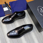 Black leather oxford shoes, angled front view with lace-up and low sole.