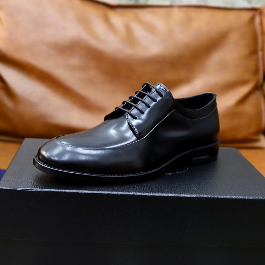Black leather oxford shoe on box, lace-up front and rubber sole.