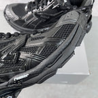 Balenciaga unisex sneaker side detail, black textured mesh with glossy trim.
