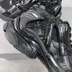 Balenciaga unisex sneaker close-up on side, black with metallic logo plate.