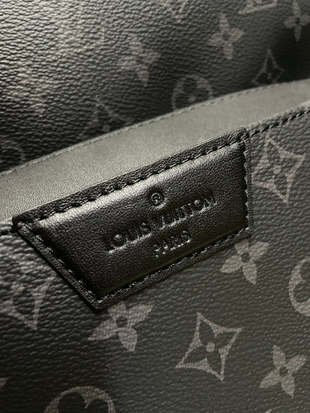 Louis Vuitton embossed logo label on black monogram leather-look panel