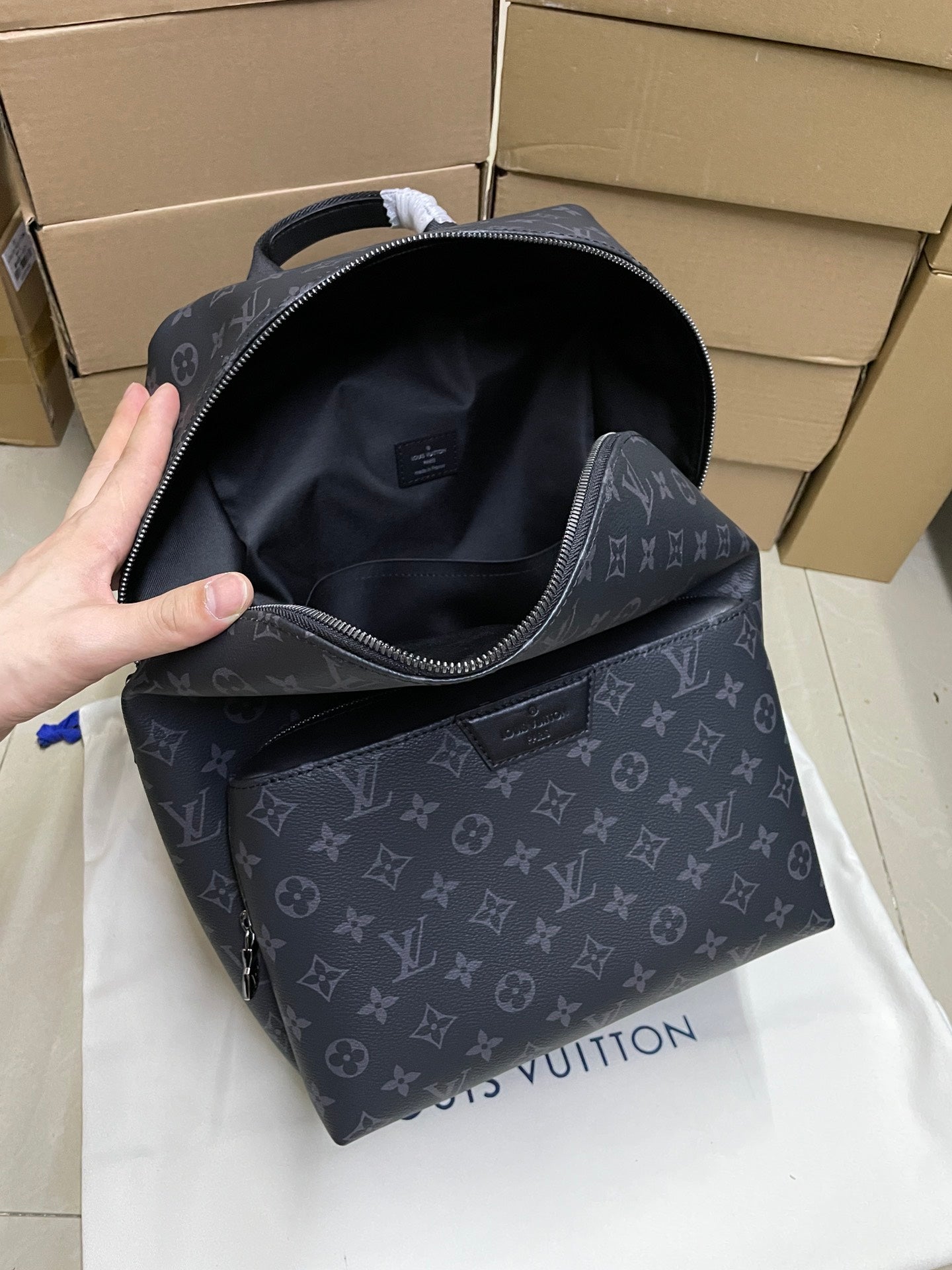 Monogram mini backpack open to show dark interior and zipper pocket