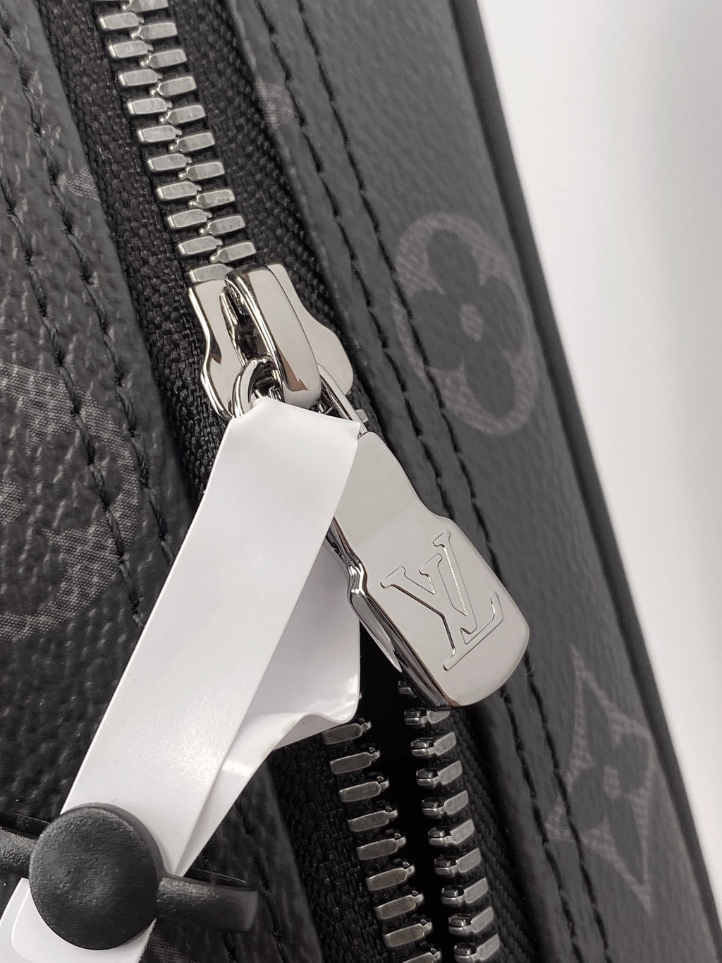 Zip pull hardware on monogram pouch with silver tone zipper teeth
