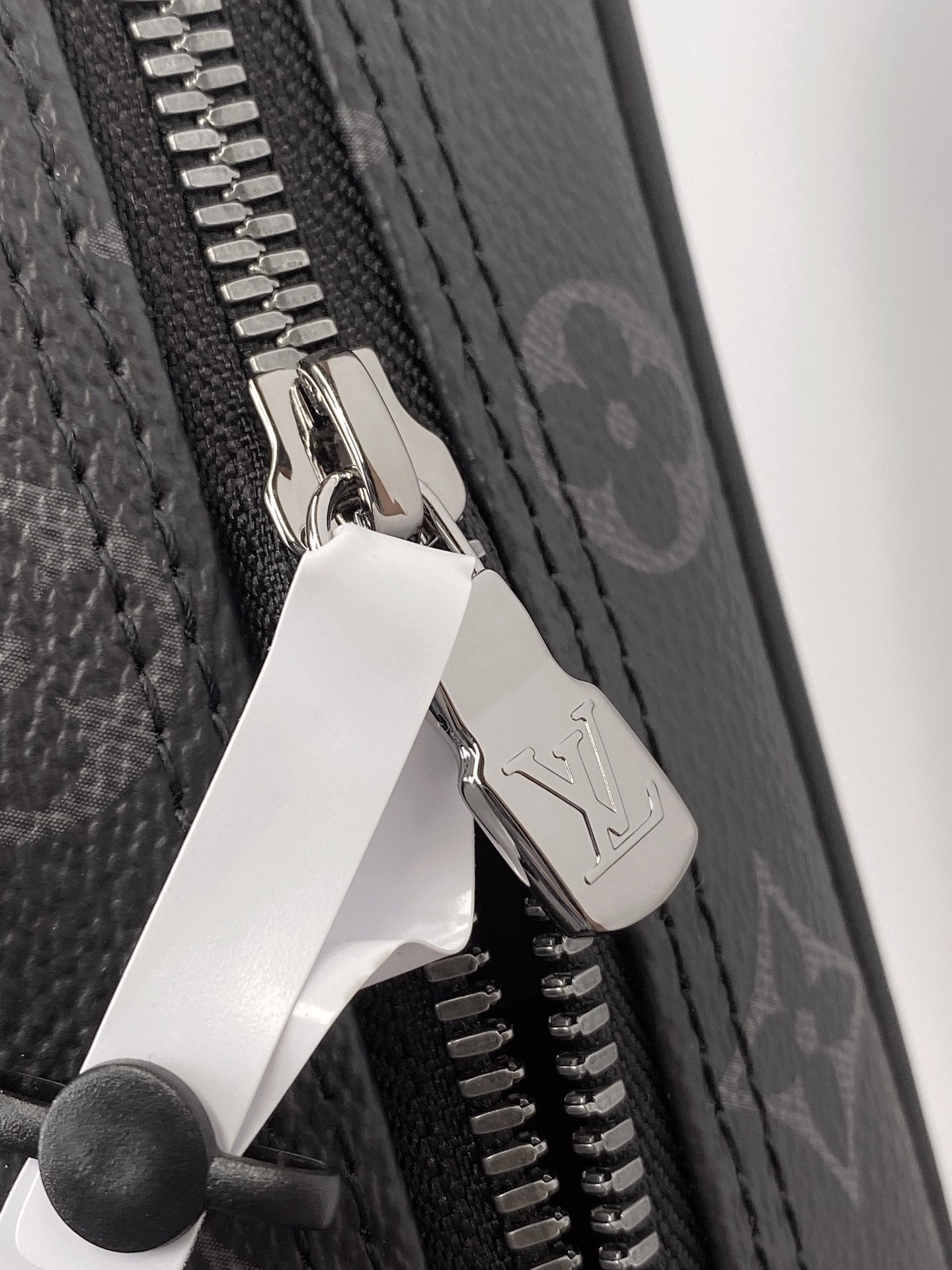 Zip pull hardware on monogram pouch with silver tone zipper teeth