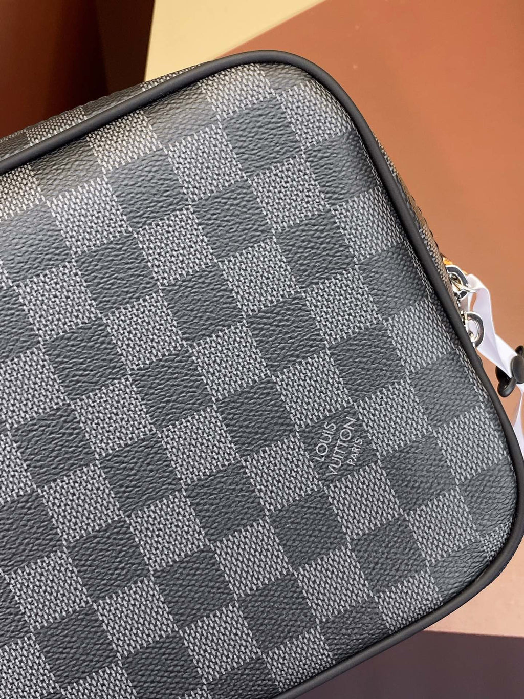 Louis Vuitton bag corner detail with dark gray checkered canvas and stitched trim