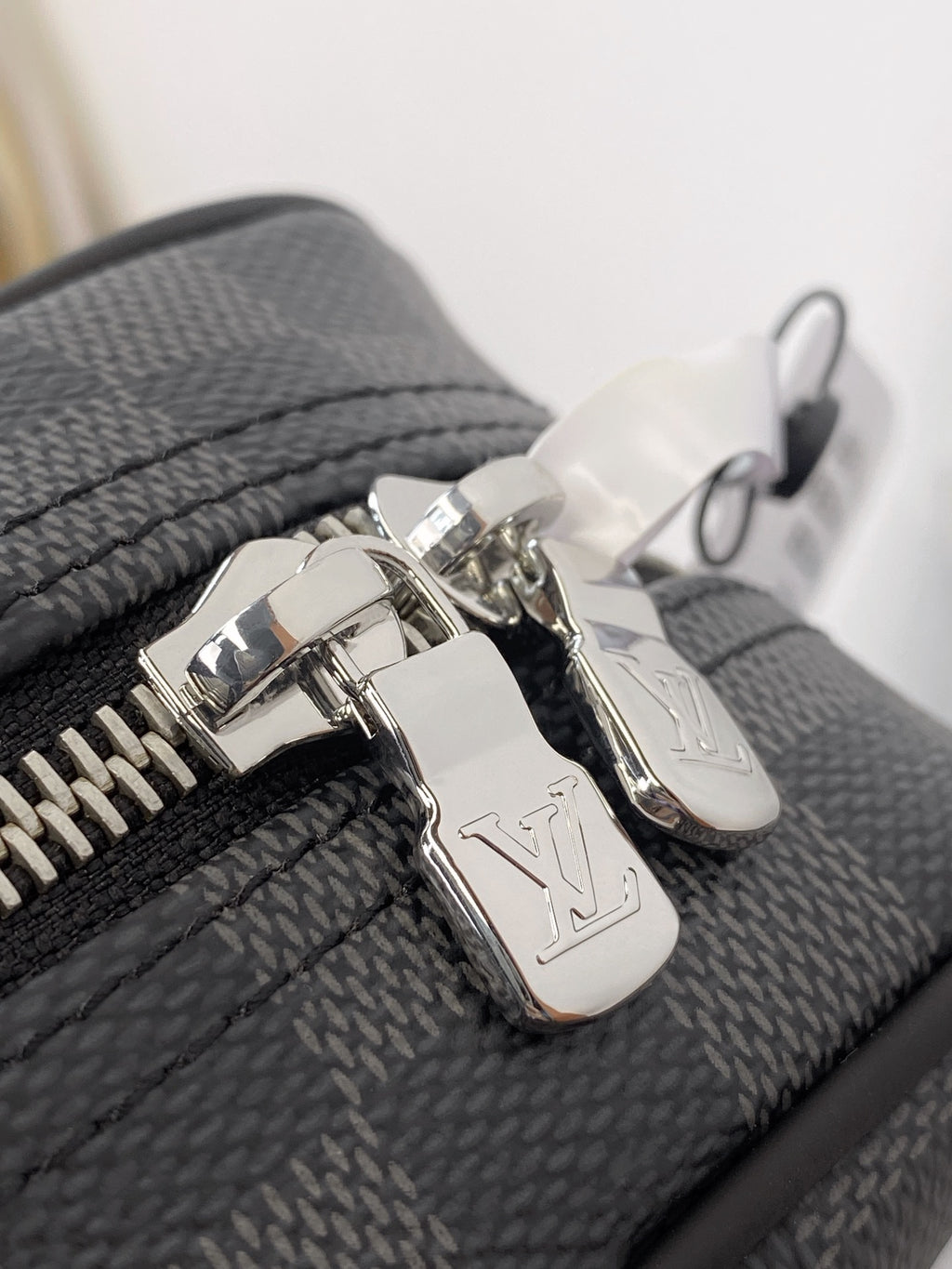 Louis Vuitton small bag hardware with silver-toned zip pulls and rings on gray canvas