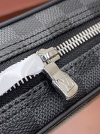 Louis Vuitton metal zipper pull on dark gray check bag, close-up.