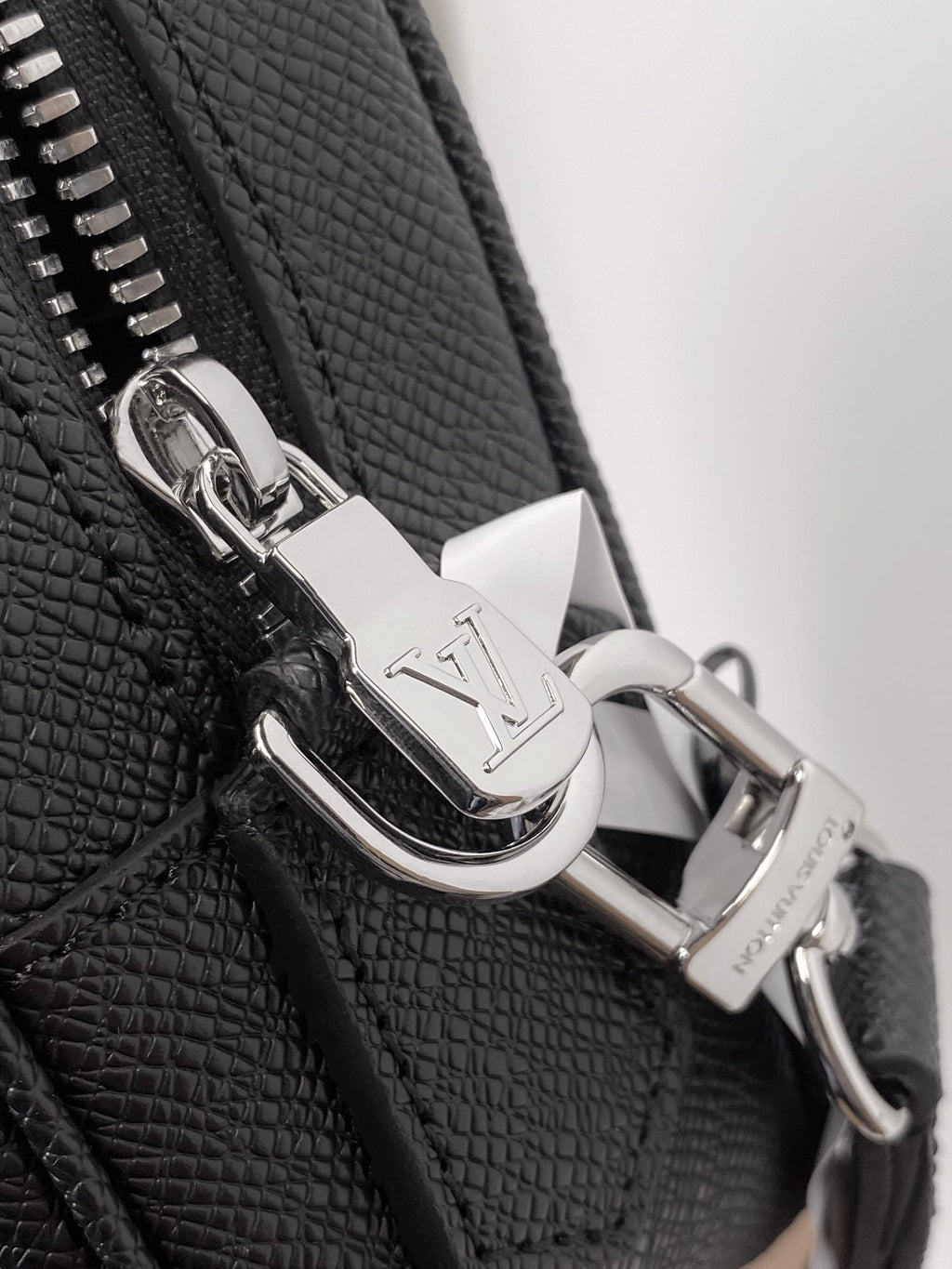 Silver metal zipper pull and snap hardware on black textured leather