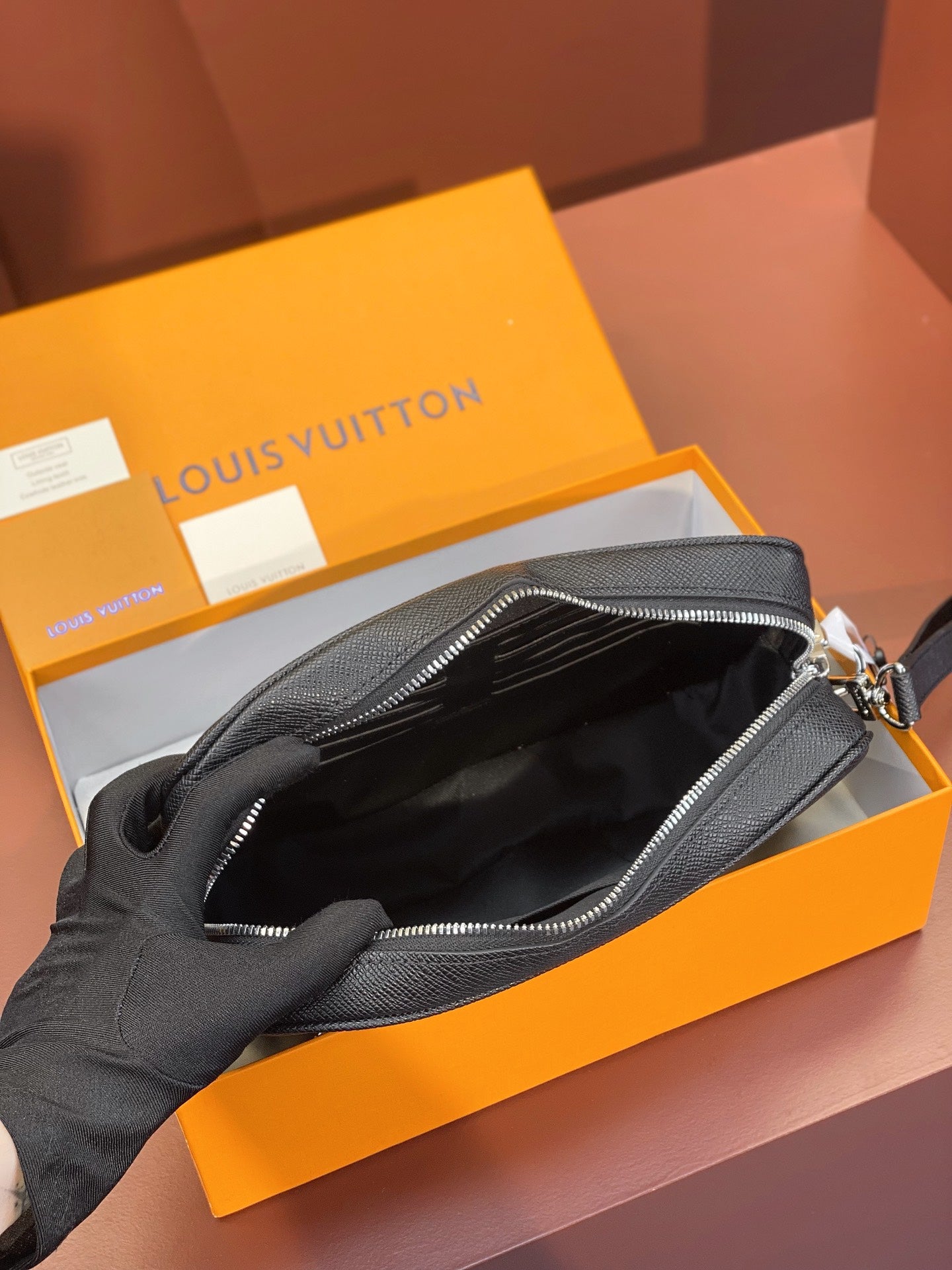 Black leather small bag open to show dark interior and zipped compartment