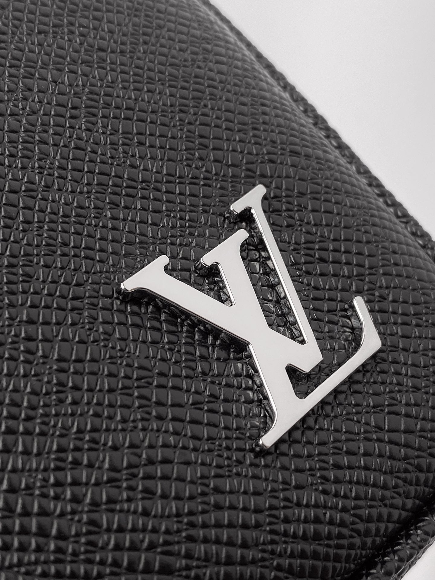 Louis Vuitton monogram metal emblem on black textured leather