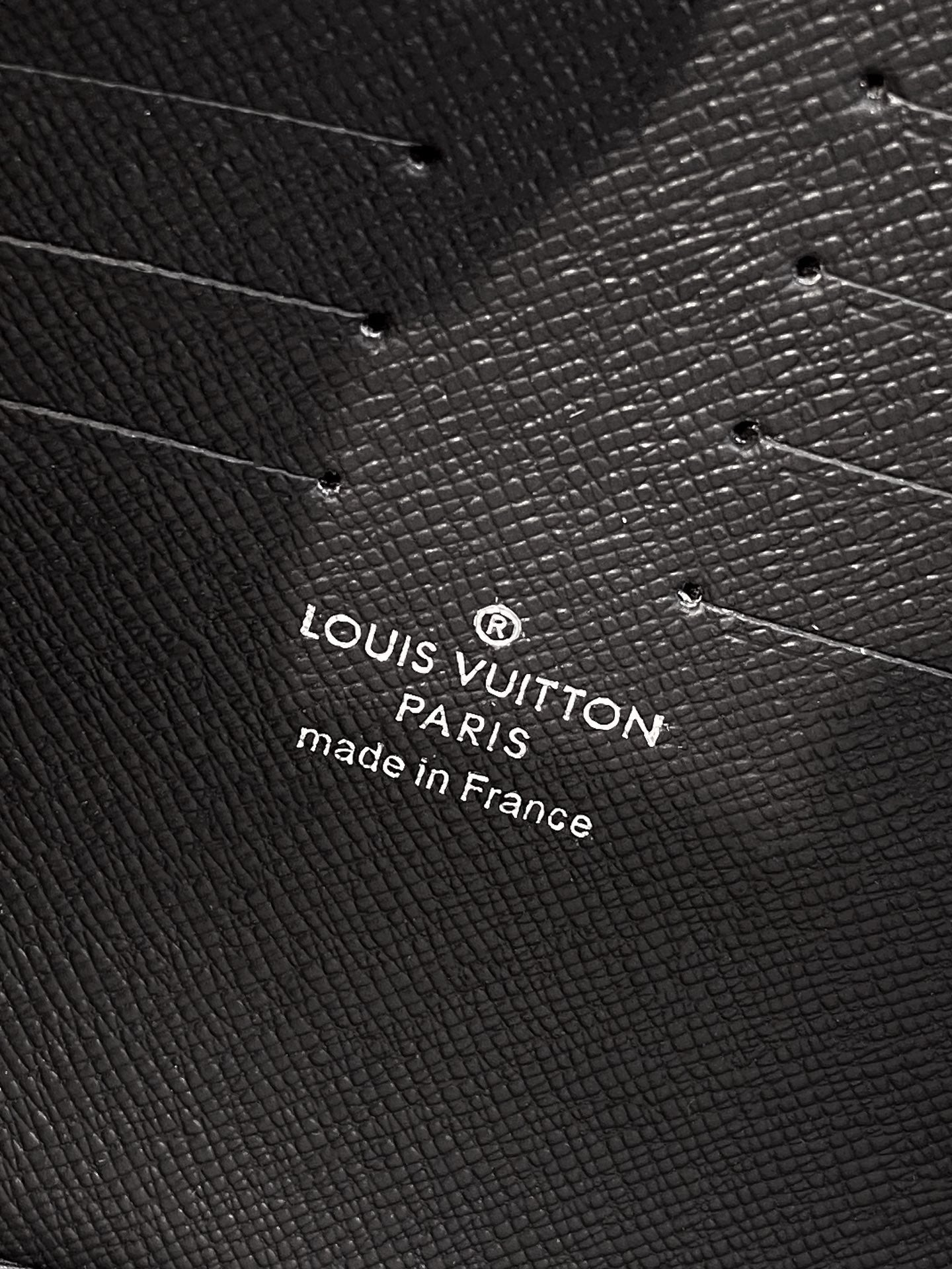 Louis Vuitton leather bag close-up with embossed logo text "Louis Vuitton Paris made in France"