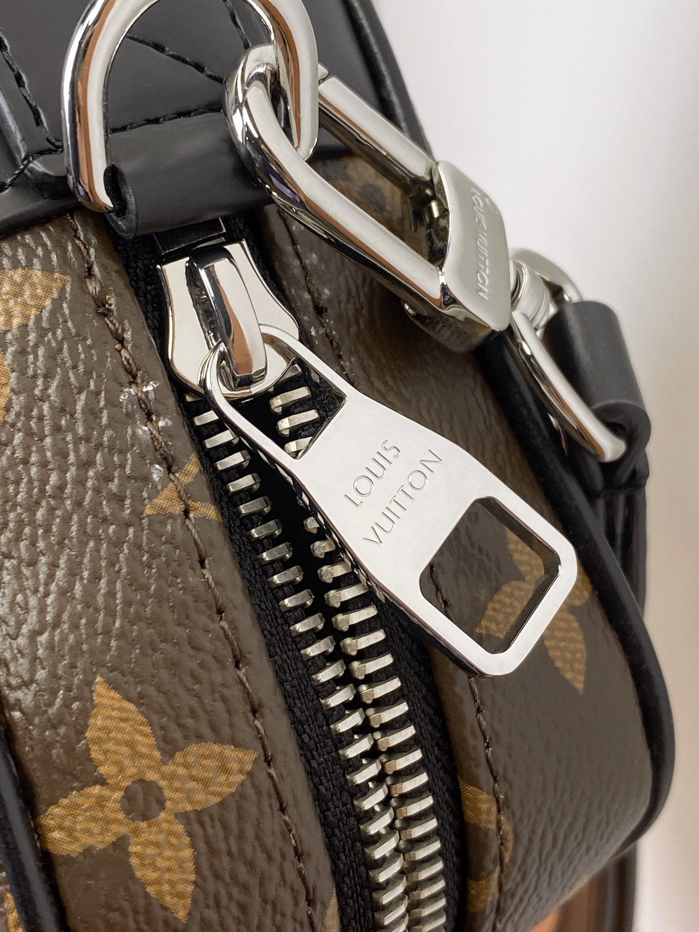 Louis Vuitton bag hardware close-up with metal clasp, D-ring, and zipper pull