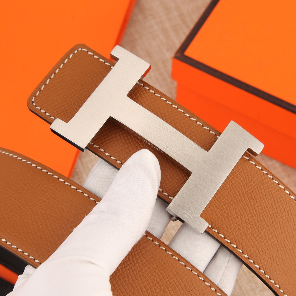 Hermes leather belt buckle close-up with tan leather and white contrast stitching