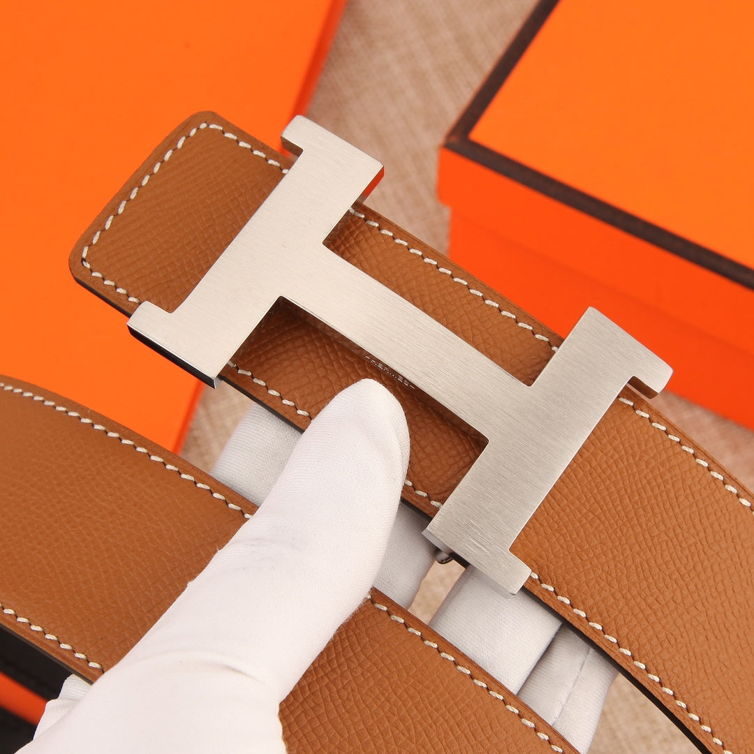Hermes leather belt buckle close-up with tan leather and white contrast stitching