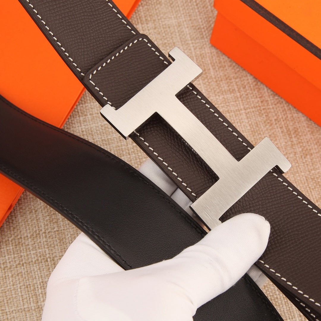 Hermes belt close-up: dark brown leather strap with silver H buckle and white stitching
