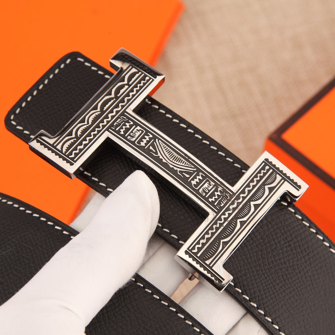 Leather belt buckle close-up showing engraved silver-tone clasp and stitched leather edge