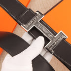 Leather belt buckle close-up with silver-tone H clasp and white edge stitching