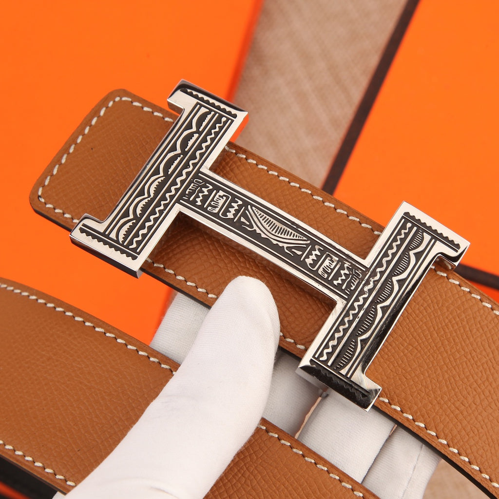 Hermes belt buckle detail on tan leather strap with white topstitching.